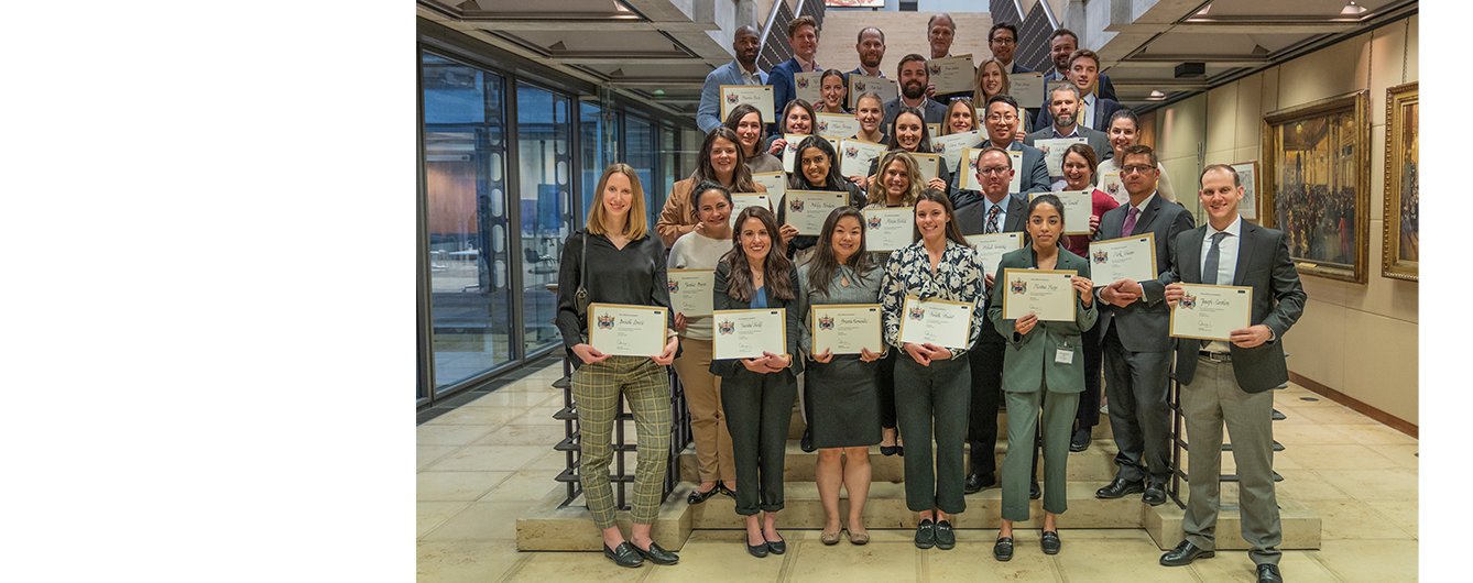 Delegates stand on steps, smiling at the camera holding their certificates
