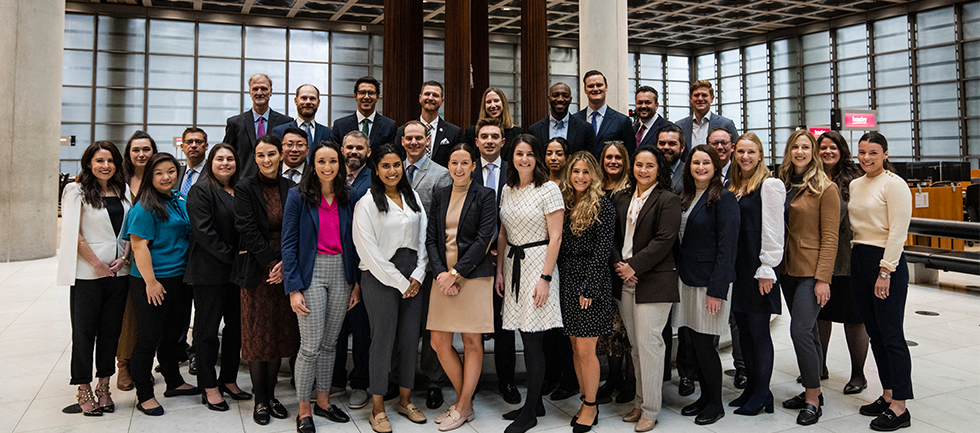 Broker academy group standing on the underwriting floor smiling at the camera
