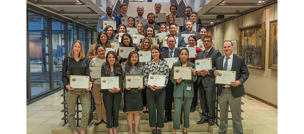 Group standing on stairs, holding their certificates, smiling at camera