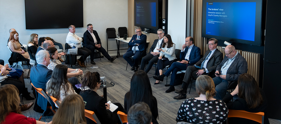 The group are sat facing a panel in a meeting room
