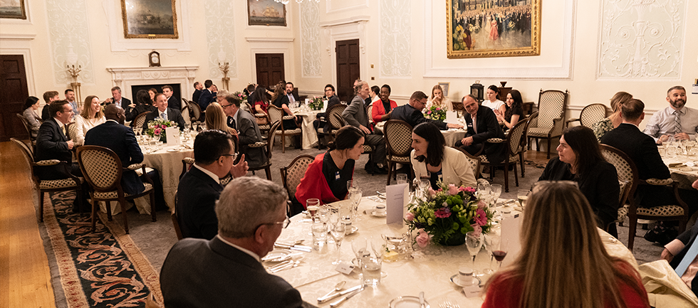 Delegates are sat around round tables in the Adam Room at Lloyd's, talking with each other while they wait for dinner to be served