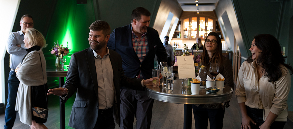 Groups of people are stood around the room networking